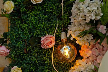 Yeşil arka planda sarı lamba. Ampullerle, çiçeklerle ve yeşilliklerle iç dekorasyon.