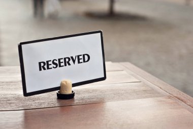 Bir bardak beyaz şarap yakın çekim. Şehrin arka planındaki ahşap bir masada alkollü içecek. Tabak masanın üzerinde..