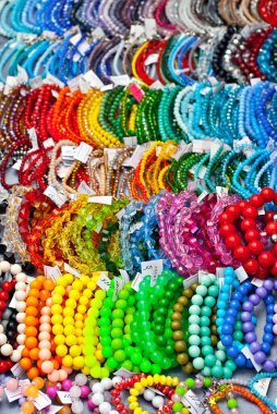 Masanın üzerinde renkli taşlardan bir kolye var. Doğal değerli minerallerden yapılmış birçok farklı mücevher ve boncuk. Boncuklu mücevherler fuarda satılıyor..