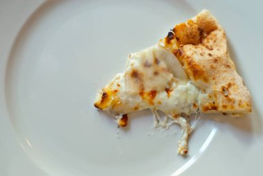 Beyaz bir tabakta üçgen pizza dilimi. Peynirli, armutlu ve çam fıstıklı pizza..