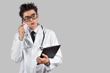 Beyaz arka planda steteskoplu bir doktor. Gözlüklü, tıbbi giysili bir adam. Doktor elinde bir tabletle şaşırdı..