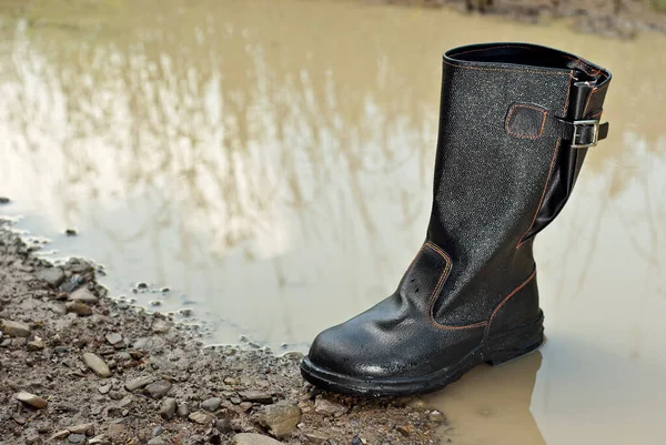 Black rubber boots close up. Boots in the swamp and dirt. The concept of cleanliness, ecology and protection. Shoes for oil workers.