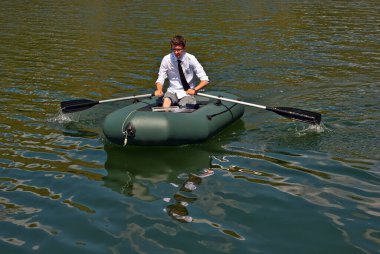 Şişme teknede beyaz gömlekli bir adam. Göl kenarında dizüstü bilgisayarı olan bir iş adamı. Uzaktan çalışma, boş zaman ve serbest çalışma kavramı..