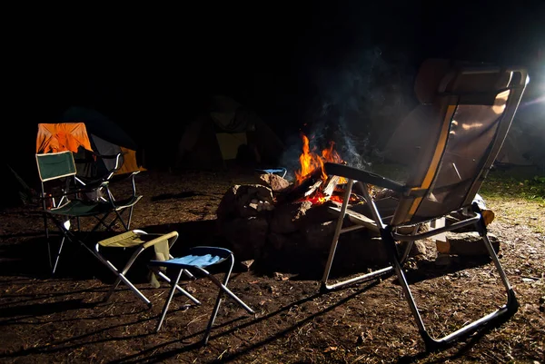 キャンプファイヤーの背景でリラックスするための空のアームチェア 火の周りのビーチチェア 自然の中で夜の休暇 — ストック写真