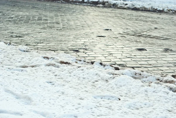 Flooded snow on the sidewalk. Early spring and melting snow. Snowy road in the city.