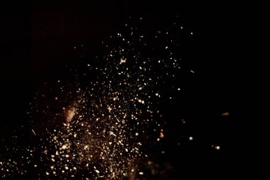 Siyah arka planda toz ve odun parçaları. Toprak parçacıkları havada uçar. Tasarım için tasarım. Bazı toz parçacıkları hareketin etkisini iletmek için bulanıklaşır.