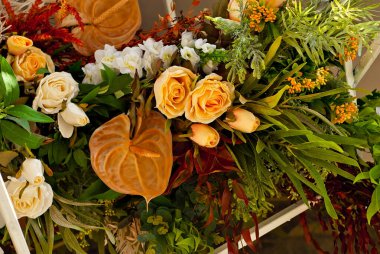 Duvarda çok renkli çiçekler ve yeşiller var. Kapatın. Yapay çiçekler iç mekanı dekore eder..