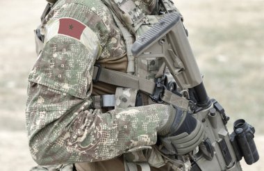 Askeri üniformalı, silahlı ve Fas bayrağı taşıyan bir asker. Kolaj. 