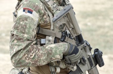 Askeri üniformalı, saldırı tüfeği ve Sırbistan bayrağı taşıyan bir asker. Kolaj. 