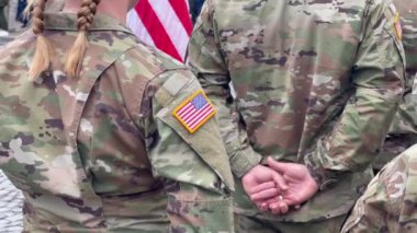 Amerikan askerleri. Amerikan ordusu. Amerikan askeri üniformasında ABD bayrağı var. Askerler tören alanının arkasında. Gaziler Günü. Anma Günü.