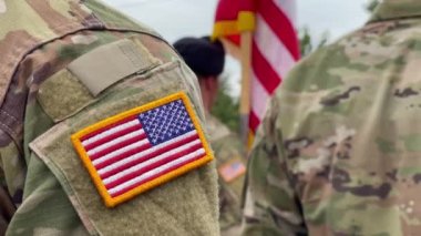 Amerikan askerleri. Amerikan ordusu. Amerikan askeri üniformasında ABD bayrağı var. Askerler tören alanının arkasında. Gaziler Günü. Anma Günü.