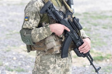 Askeri üniformalı Ukrayna askeri, saldırı tüfeği ve Ukrayna bayrağı taşıyan asker. AK tüfekli Ukraynalı asker.
