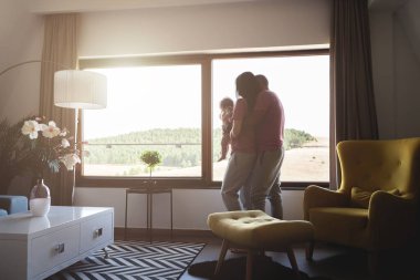 Evin penceresinin yanında duran üç kişilik melez bir aile.