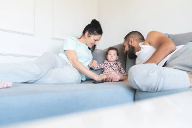 Sevgi dolu ebeveynler, evdeki kanepede kızlarıyla vakit geçiriyorlar.