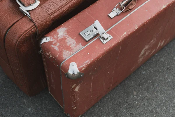 Brown vintage travel suitcase. An old worn luggage bag on the road. Restoration needed.