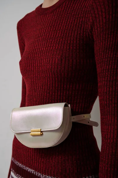 Slim girl in red sweater with leather pearl handbag. White fashionable luxury waist bag. Vertical photo.