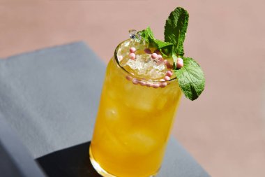 Pembe yuvarlak şeker ve nane ile süslenmiş ferahlatıcı güzel bir limonata. Balkonda buzlu sarı kokteyl. Yaz içeceği.