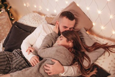 Noel 'de yatakta sevgi dolu bir çift kucaklaşması. Aşk, ilişkiler, duygular.