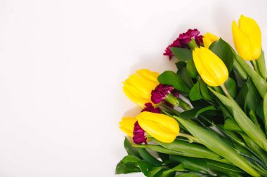 Sarı lalelerden bir buket çiçek ve beyaz arka planda izole edilmiş pembe küçük karanfiller..