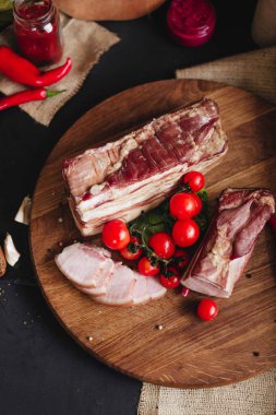 Dilimlenmiş domuz pastırması, mutfak masasındaki ahşap tahtada kiraz domatesleri..