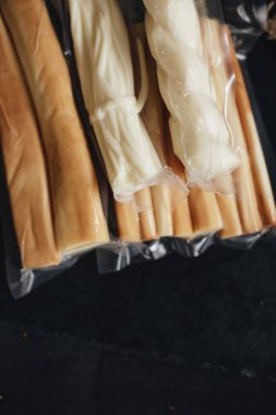 Siyah arka planda füme peynir. Süpürge peyniri paketleri.
