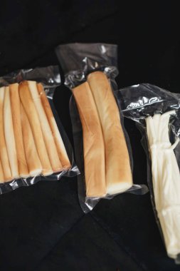 Siyah arka planda füme peynir. Süpürge peyniri paketleri.