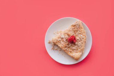 Napolyon 'un ahududulu keki. Pembe arka planda beyaz bir tabakta puf böreği dilimi. Boşluğu kopyala. 