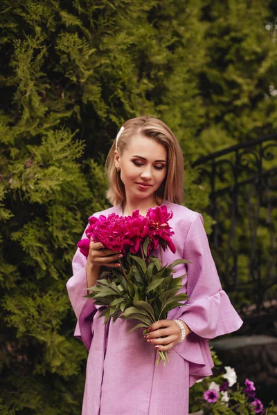 Krásná Mladá Žena Růžových Lněných Šatech Drží Rukou Růžové Pivoňky — Stock fotografie