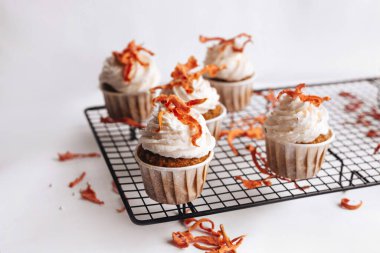 Havuçlu kek. Siyah metal kafesli havuçlu kekler ve beyaz arka planda çiçekler. Tatlı ev yapımı kekler..