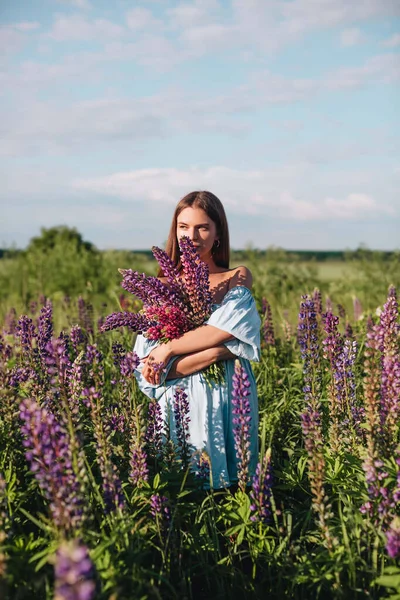 Krásná Dívka Dlouhými Vlasy Modrých Šatech Drží Kytici Lupinů Poli — Stock fotografie