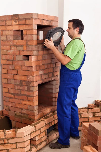 Worker building a masonry heater - trying on an iron and glass d — Stock Photo, Image