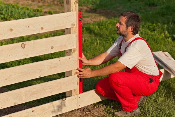 Чоловік будує дерев'яний паркан — стокове фото