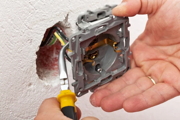 Electrician hand mounting a wall fixture — Stock Photo, Image