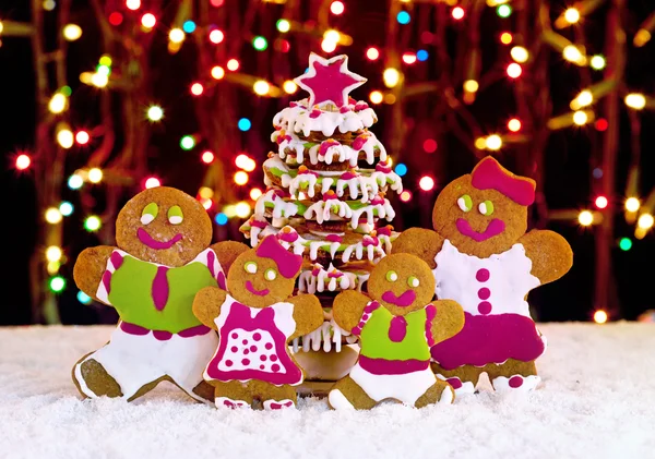 Gingerbread cookie family in front of christmas tree — Stock Photo, Image