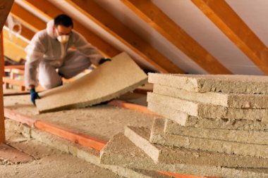 Man laying thermal insulation layer under the roof clipart