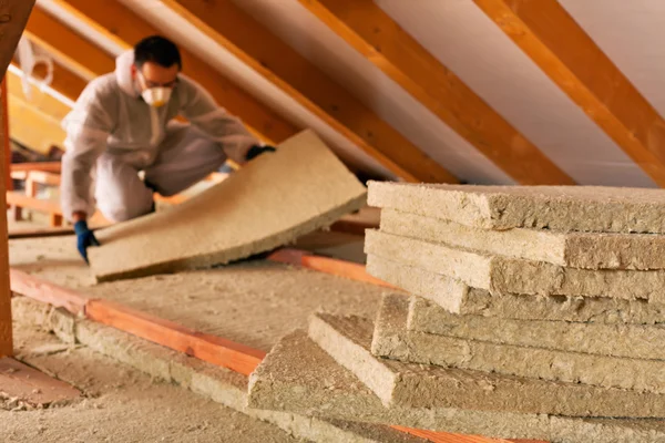 Man laying thermal insulation layer under the roof — Stock Photo, Image