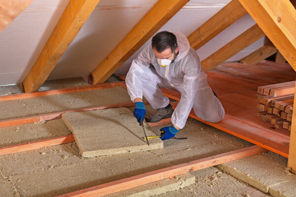 Man laying thermal insulation layer - cutting the panels