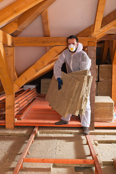 Man laying thermal insulation layer under the roof