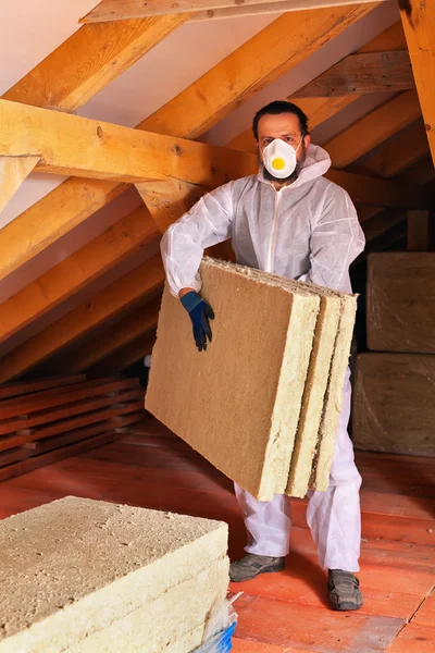 Homem que coloca camada de isolamento térmico sob o telhado — Fotografia de Stock