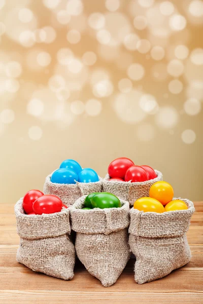 Colorful easter eggs in burlap bags — Stock Photo, Image