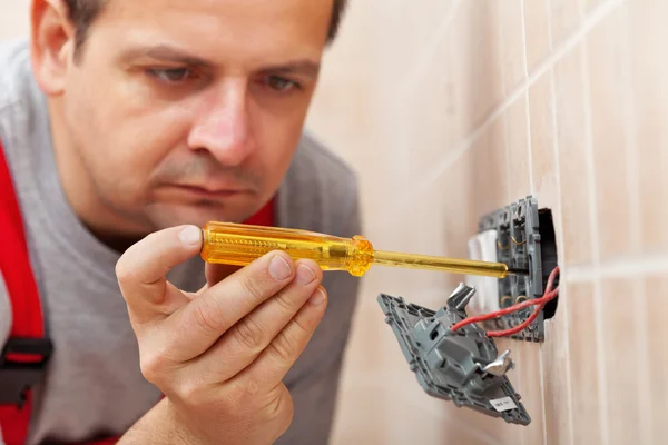 Elektriker überprüft Wandhalterung mit Spannungsprüfer — Stockfoto