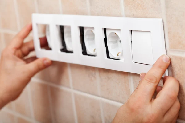 Mãos instalando moldura decorativa em soquetes elétricos — Fotografia de Stock