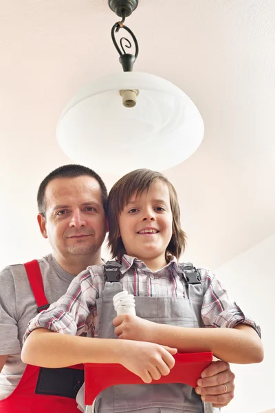 Son helping father changing a lightbulb — Stock Photo, Image