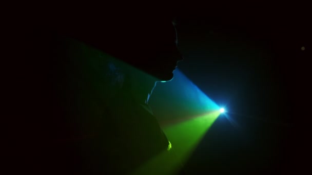 Bild av ung flicka på ljus bakgrund av olika färger som rör sig i mörkret. Flickan vänder ryggen till Ljuset gradvis stänga det. — Stockvideo