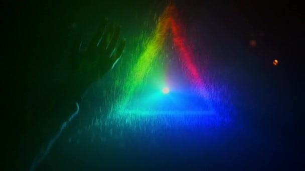 Un incroyable triangle. Main se déplace sur fond de triangle avec de la lumière colorée. Des éclaboussures d'eau volent à portée de main. — Video