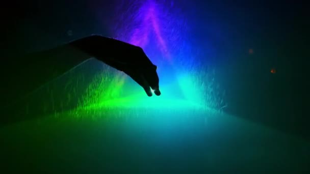 Un Triángulo Increíble. La mano se mueve sobre el fondo del triángulo con luz de color. Salpicaduras de agua vuelan en la mano. — Vídeos de Stock