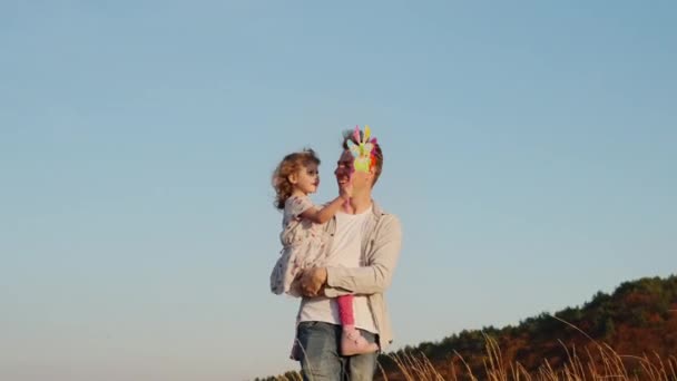 Férias em família na natureza. Pai segura pequena filha e seu filho corre ao redor. — Vídeo de Stock