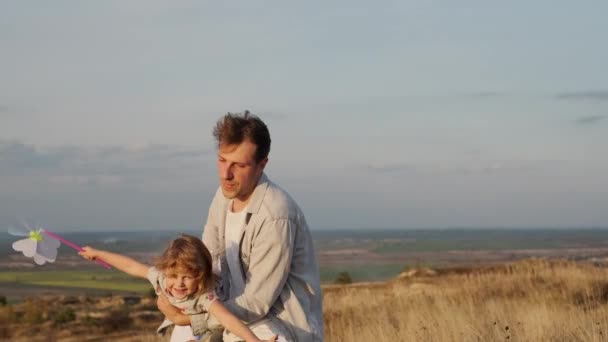 Familienurlaub in der Natur. Papa hält kleine Tochter und sein Sohn läuft herum. Mann verdreht seine Tochter, als ob sie fliegen würde. — Stockvideo