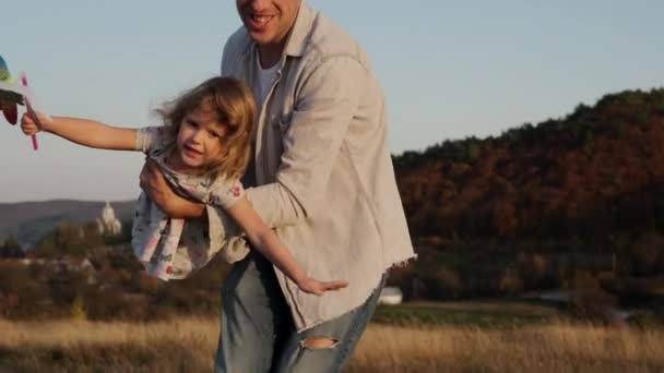 Familie vakantie in de natuur. Papa houdt een dochtertje vast en zijn zoon rent rond. Man Twists zijn dochter alsof ze vliegen. — Stockvideo