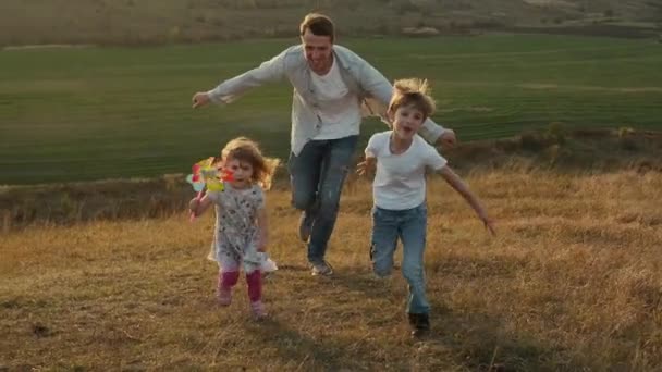 Papà raggiunge la sua figlioletta e suo figlio. Si divertono nella natura. — Video Stock